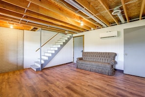 Ein Zimmer mit einer Holztreppe, einem Sofa und einer Klimaanlage.