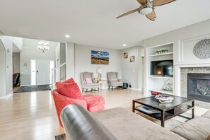 A spacious living room with a fireplace, a television, and a ceiling fan. - 5,000 Sq Ft Luxury Mansion (Erie)