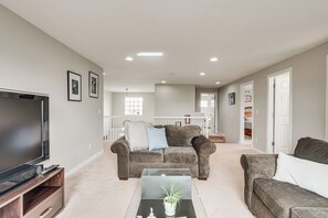 A living room with a TV, two sofas, a coffee table, and a staircase leading to another room. - 5,000 Sq Ft Luxury Mansion (Erie)