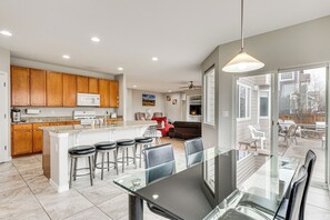 A modern kitchen with wooden cabinets, a central island with bar stools, and a dining area with a glass table and chairs. - 5,000 Sq Ft Luxury Mansion (Erie)