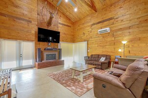 Un salón amplio con chimenea, un televisor de pantalla plana montado en la pared y una zona de estar confortable con sofá y sillón reclinable.