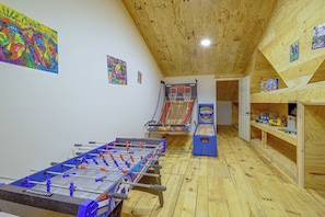 A room with a foosball table, a basketball hoop, and a Connect4 game. - Lakefront Greers Ferry Rustic Getaway w/ Game Room (Higden)