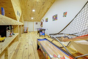 Una habitación con piso de madera, una mesa de ping pong, un sofá y una zona con mosquitero.