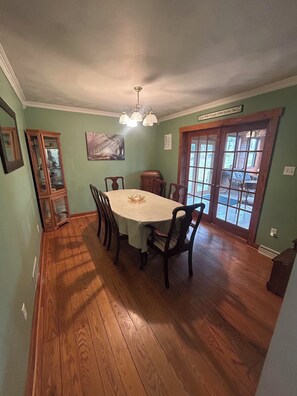 A dining room with a wooden table and chairs, a chandelier, and a view through a glass door. - 2BR + spacious loft. Rich Hill Retreat offers spectacular mountain view. (Connellsville)