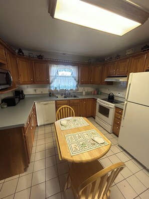 A kitchen with wooden cabinets, a white refrigerator, a stove, and a sink. - 2BR + spacious loft. Rich Hill Retreat offers spectacular mountain view. (Connellsville)