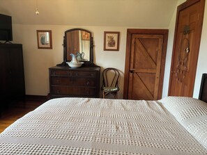 A bedroom with a large bed, a dresser with a mirror, a chair, and a wooden door. - 2BR + spacious loft. Rich Hill Retreat offers spectacular mountain view. (Connellsville)