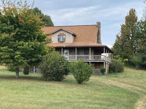 A two-story house with a porch, surrounded by trees and grass. - 2BR + spacious loft. Rich Hill Retreat offers spectacular mountain view. (Connellsville)