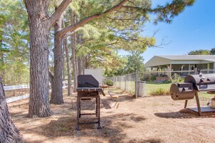 A backyard with a barbecue grill, a picnic table, and a fenced area.