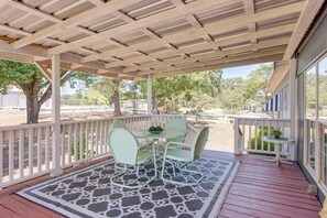 A covered outdoor patio with a table and chairs, a patterned rug, and a view of trees and a fence in the background. - Walk to Beach & Dock! Lake Texoma Family Getaway (Kingston)