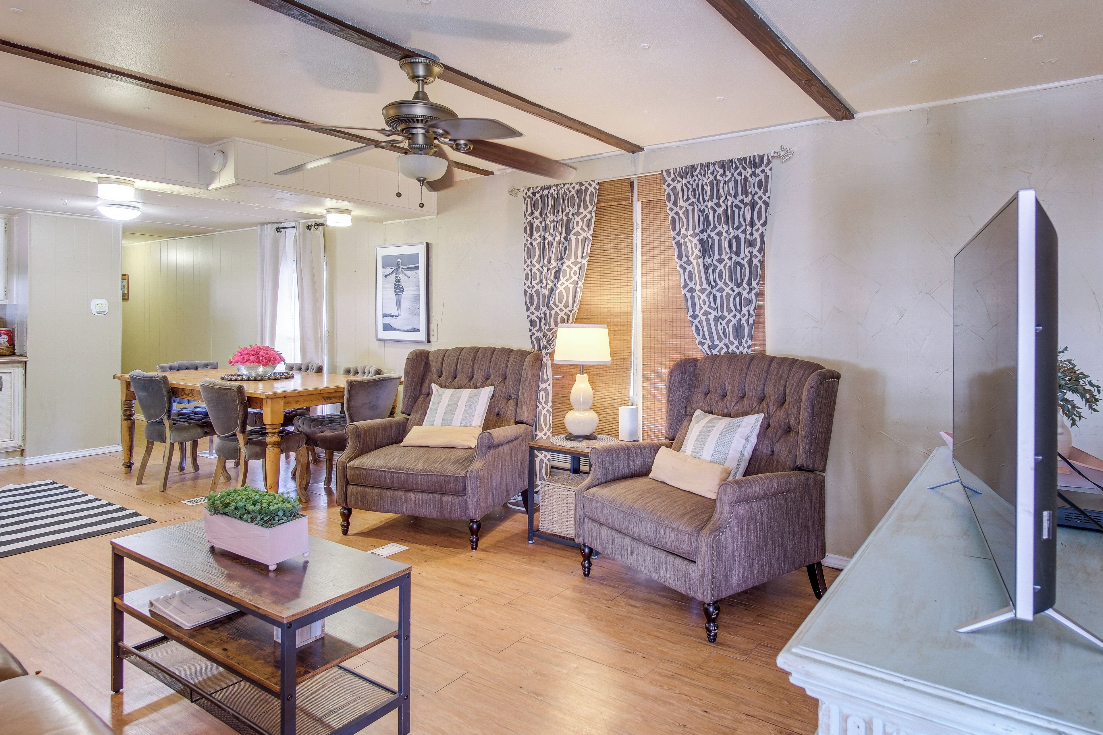 A living room with two armchairs, a coffee table, a television, and a dining area with a table and chairs.