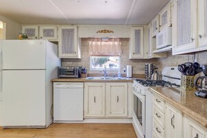 A kitchen with a refrigerator, microwave, stove, sink, and cabinets.