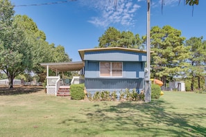 A small, single-story house with a porch and a fenced yard. - Walk to Beach & Dock! Lake Texoma Family Getaway (Kingston)