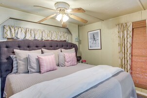 A bedroom with a large bed, a ceiling fan, and a window with curtains.