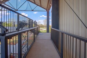 A covered outdoor corridor with metal railings, a concrete floor, and a view of the surrounding landscape. - Denton Couples' Studio on 100-acre Ranch (Denton)