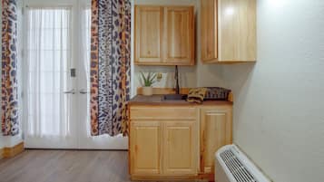Una cocina con armarios de madera, un lavamanos, una encimera y un ventanal con cortinas estampadas.