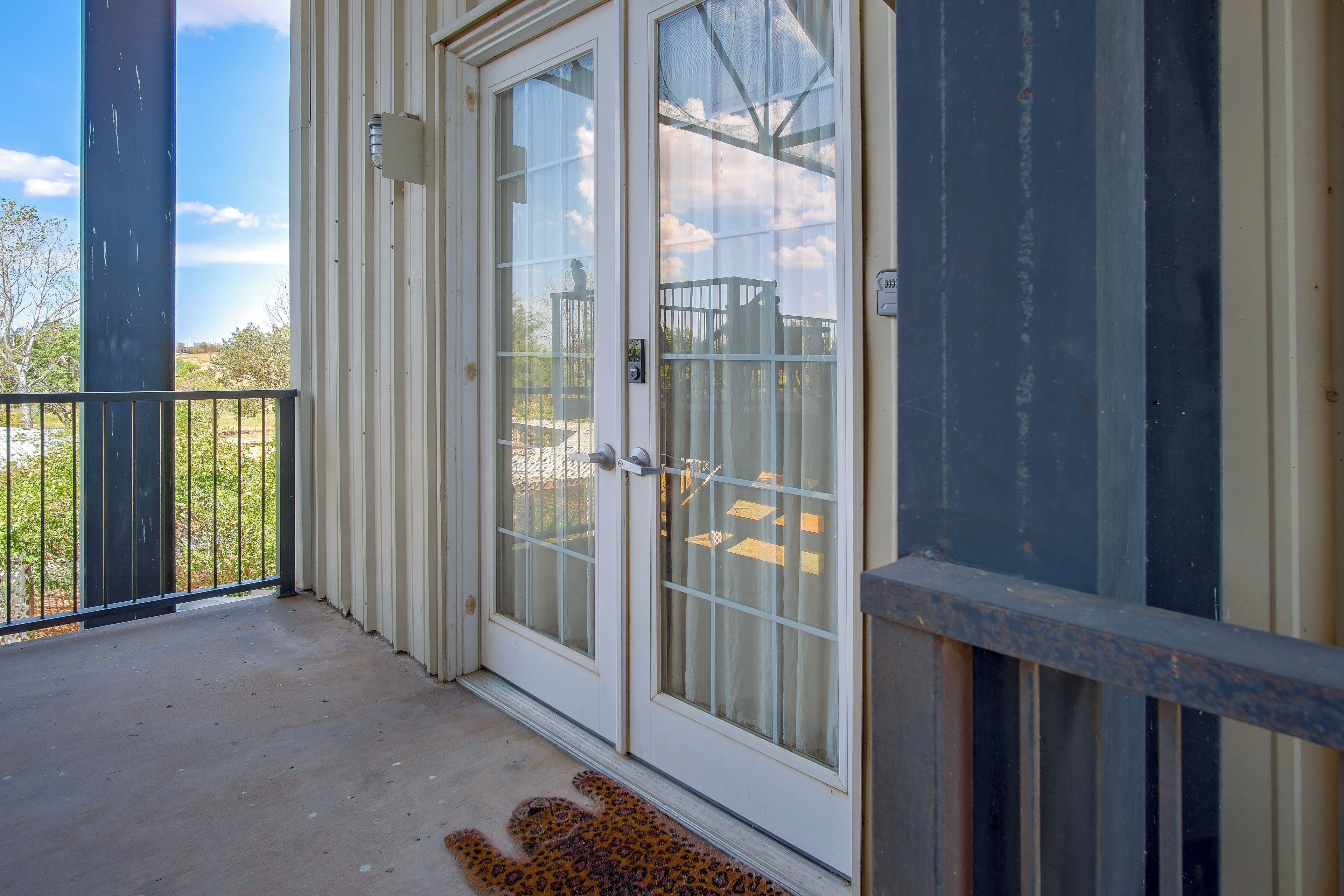 A residential building with a sliding glass door, a metal railing, and a concrete floor.