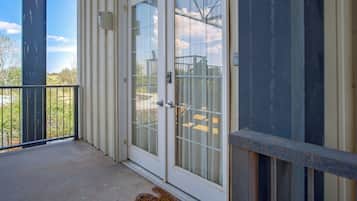 A residential building with a sliding glass door, a metal railing, and a concrete floor.