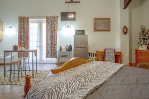 A bedroom with a bed, a desk, a chair, a refrigerator, and a television.
