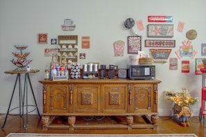Una estación de café con diversas máquinas de café y tazas, una máquina de palomitas de maíz y un televisor antiguo.