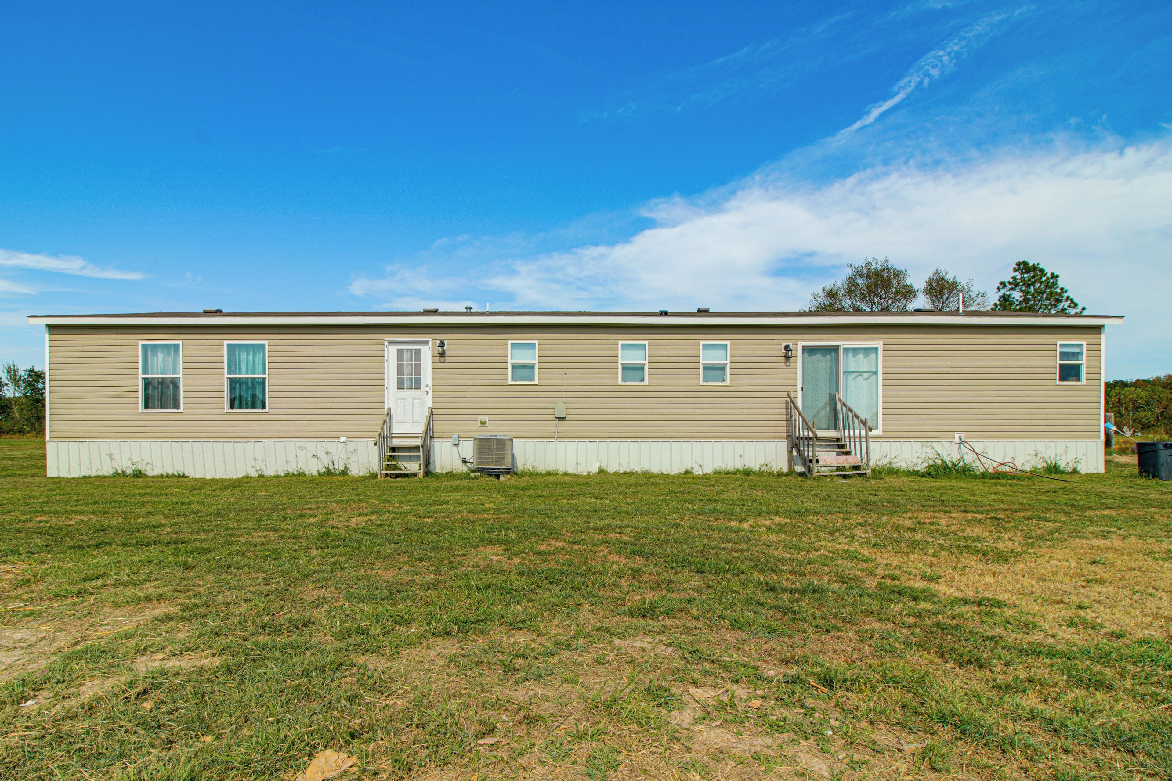 A single-story mobile home with a front door, two windows on the side, and a small porch area.