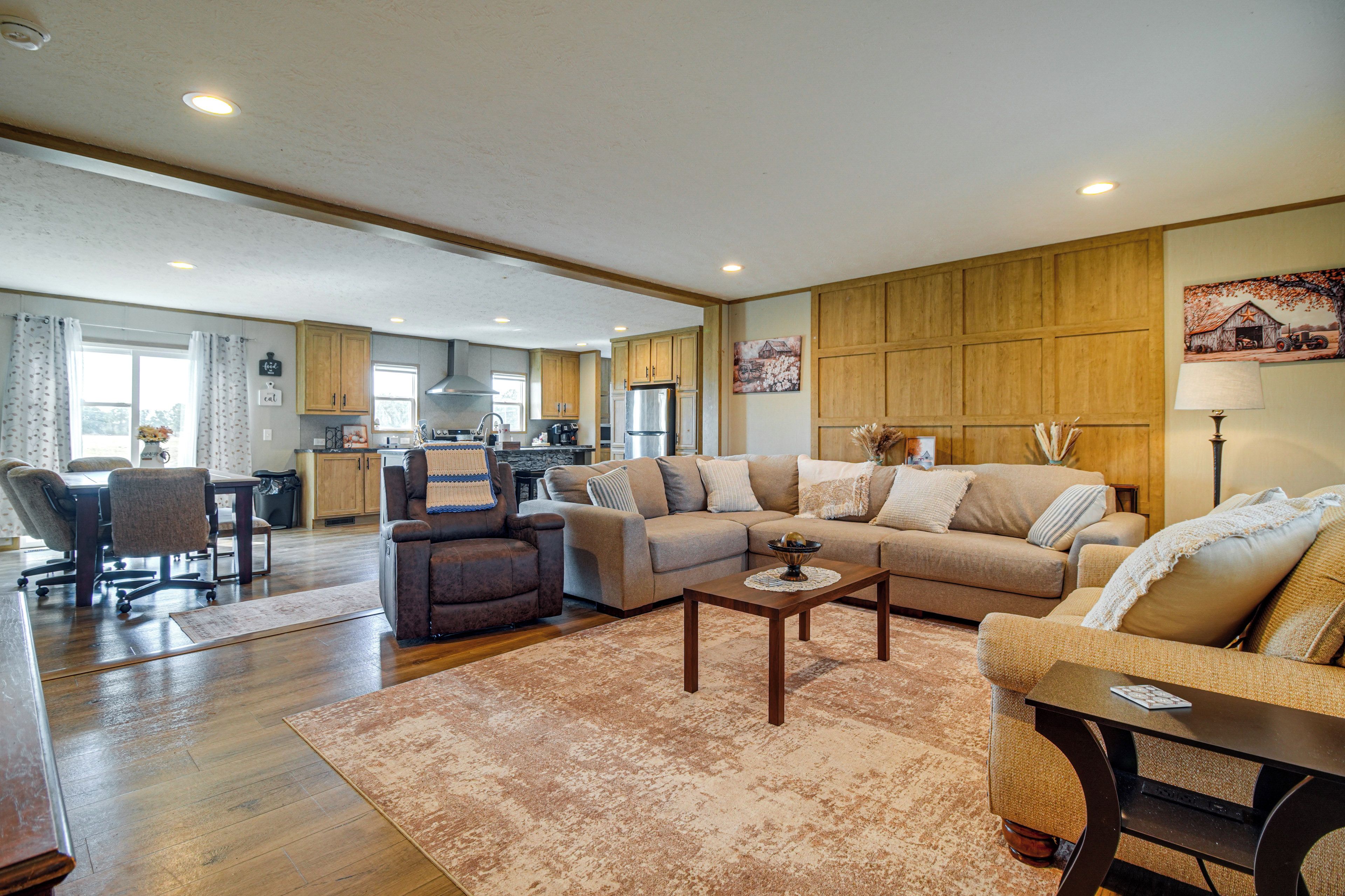 A spacious living room with a large sectional sofa, a coffee table, and a dining area with a table and chairs.