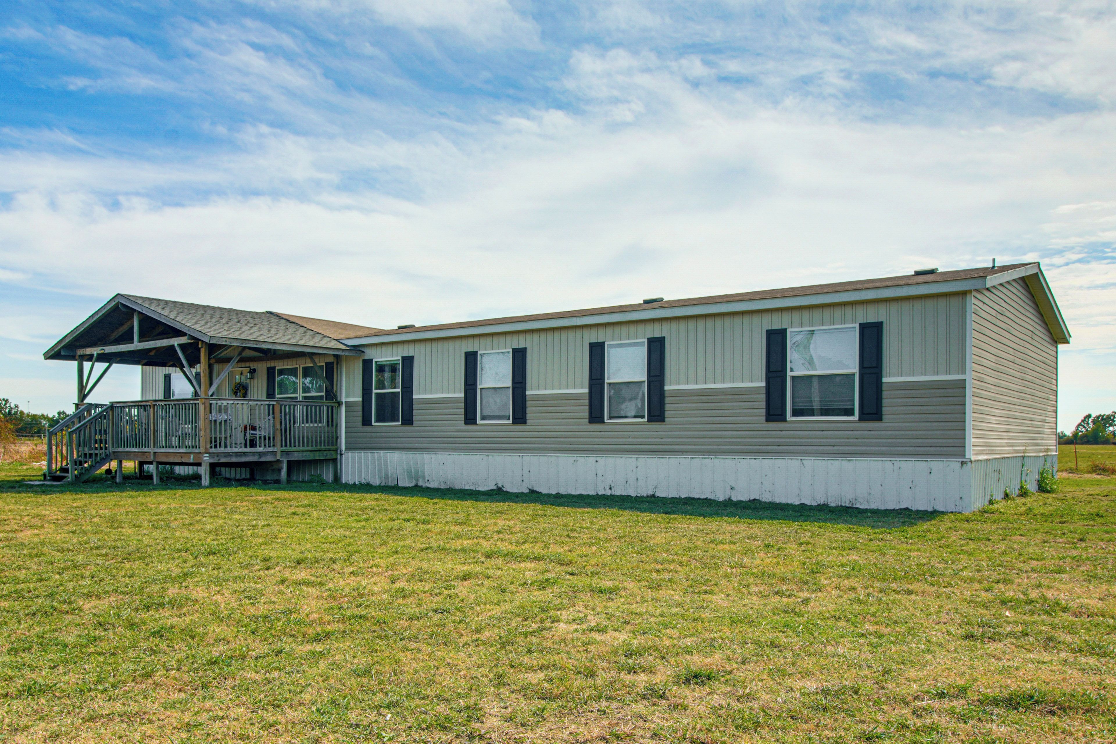 A single-story mobile home with a porch and a fenced yard.