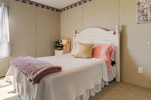 Ein Schlafzimmer mit einem Bett, einem Nachttisch, einer Lampe und einer Wanddekoration.