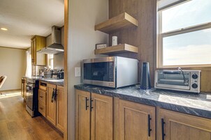 Una cucina con mobili in legno, un forno a microonde, un tostapane e una finestra che offre luce naturale.