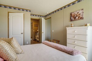 Una camera da letto con un letto, una cassettiera, una sedia e una porta che dà su un bagno.