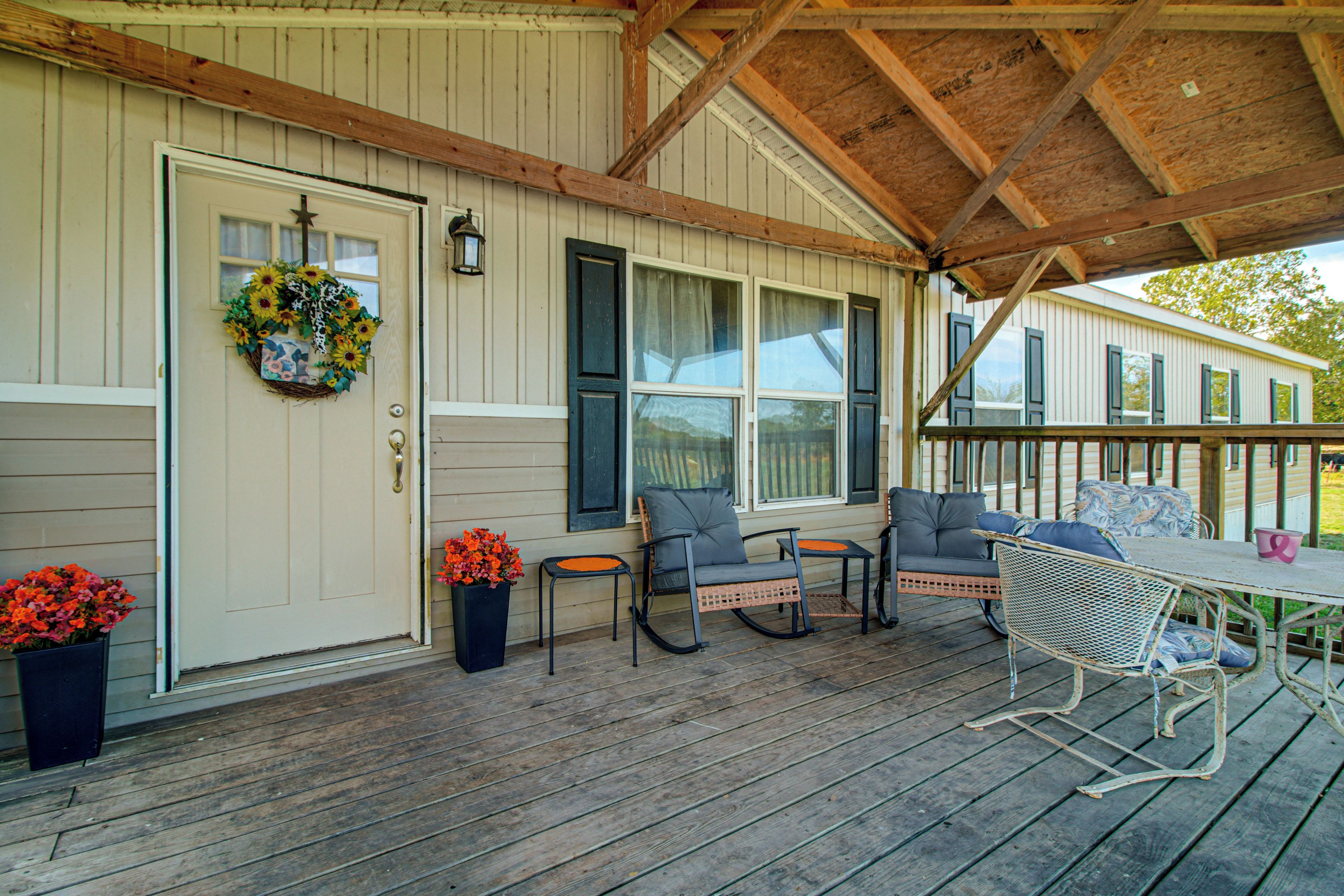 A covered porch with a wooden floor, a table, and four chairs.