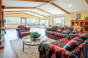 A spacious living room with high ceilings, built-in seating, and large windows.