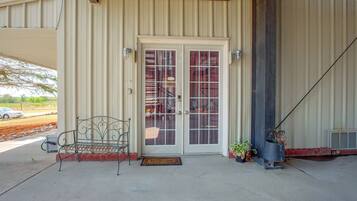 A building entrance with a metal bench, a welcome mat, and potted plants.