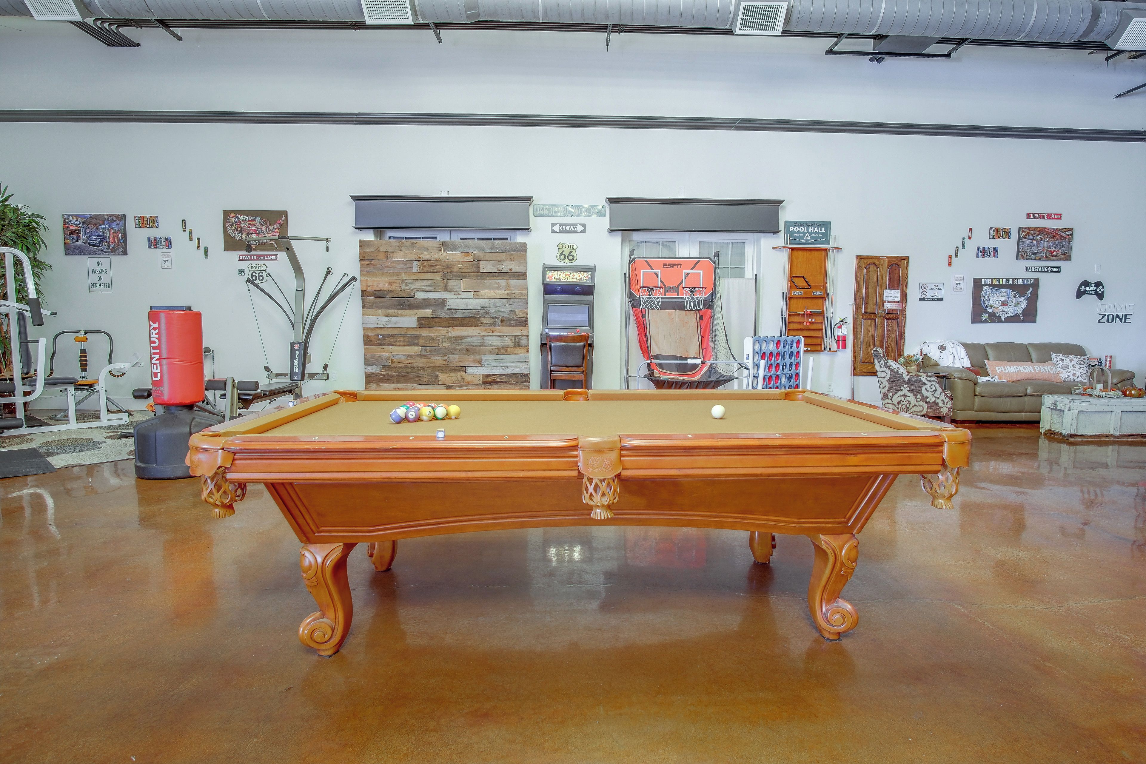 A pool table in a room with a wooden wall, a door, and various wall decorations.