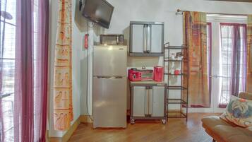 A compact kitchen with a refrigerator, microwave, and a small coffee maker.