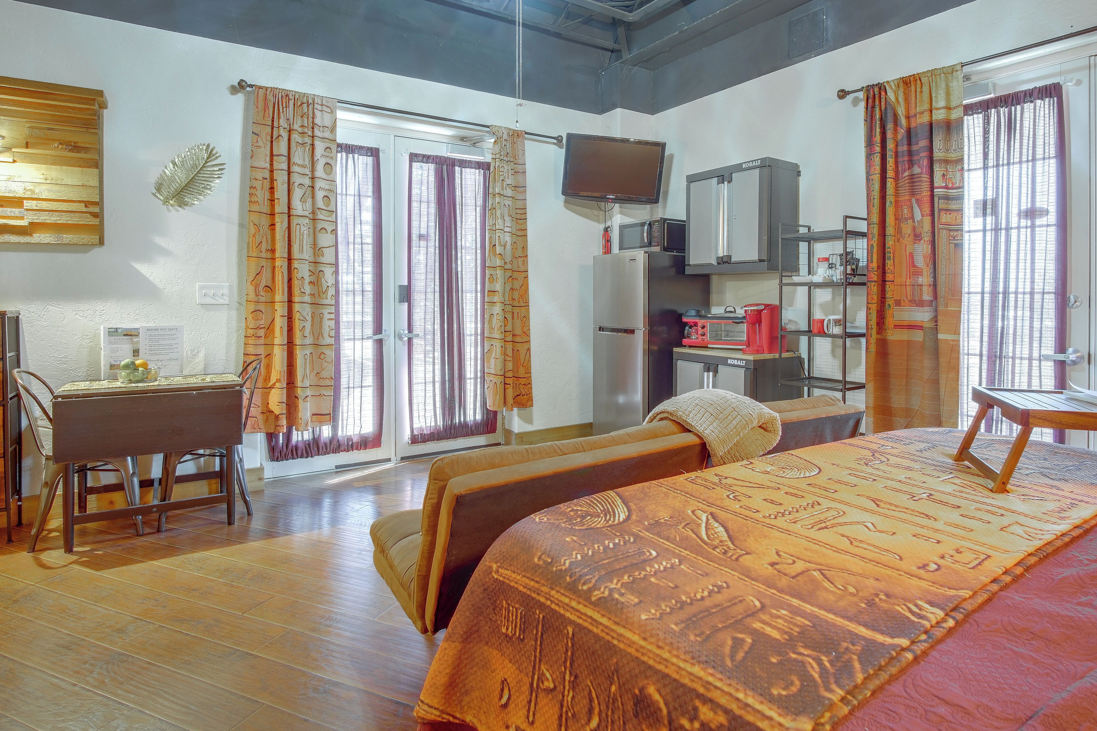 A hotel room with a bed, a desk, a television, a refrigerator, and a microwave.