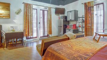 A hotel room with a bed, a desk, a television, a refrigerator, and a microwave.