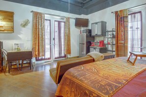 Quarto de hotel com cama, escrivaninha, televisão, frigorífico e micro-ondas.