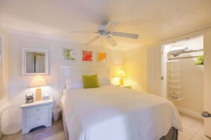 A hotel room with a bed, bedside lamps, a ceiling fan, a door with a towel rack, and a wall with framed artwork. - Naples Duplex Bundle By Shopping & Beaches (Naples)