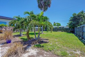 A residential backyard with palm trees, a wooden fence, and a clear blue sky. - Naples Duplex Bundle By Shopping & Beaches (Naples)