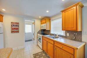A kitchen with wooden cabinets, a microwave, a stove, and a sink. - Naples Duplex Bundle By Shopping & Beaches (Naples)