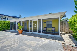 A covered outdoor seating area with a potted plant, a sign reading 'THE COZY,' and a wooden fence. - Naples Duplex Bundle By Shopping & Beaches (Naples)
