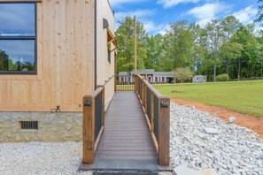 A wooden deck leading to a building with a stone foundation.