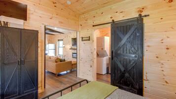 A wooden interior with a bed, a wardrobe, and a kitchen area.