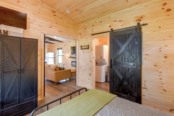A wooden interior with a bed, a wardrobe, and a kitchen area.