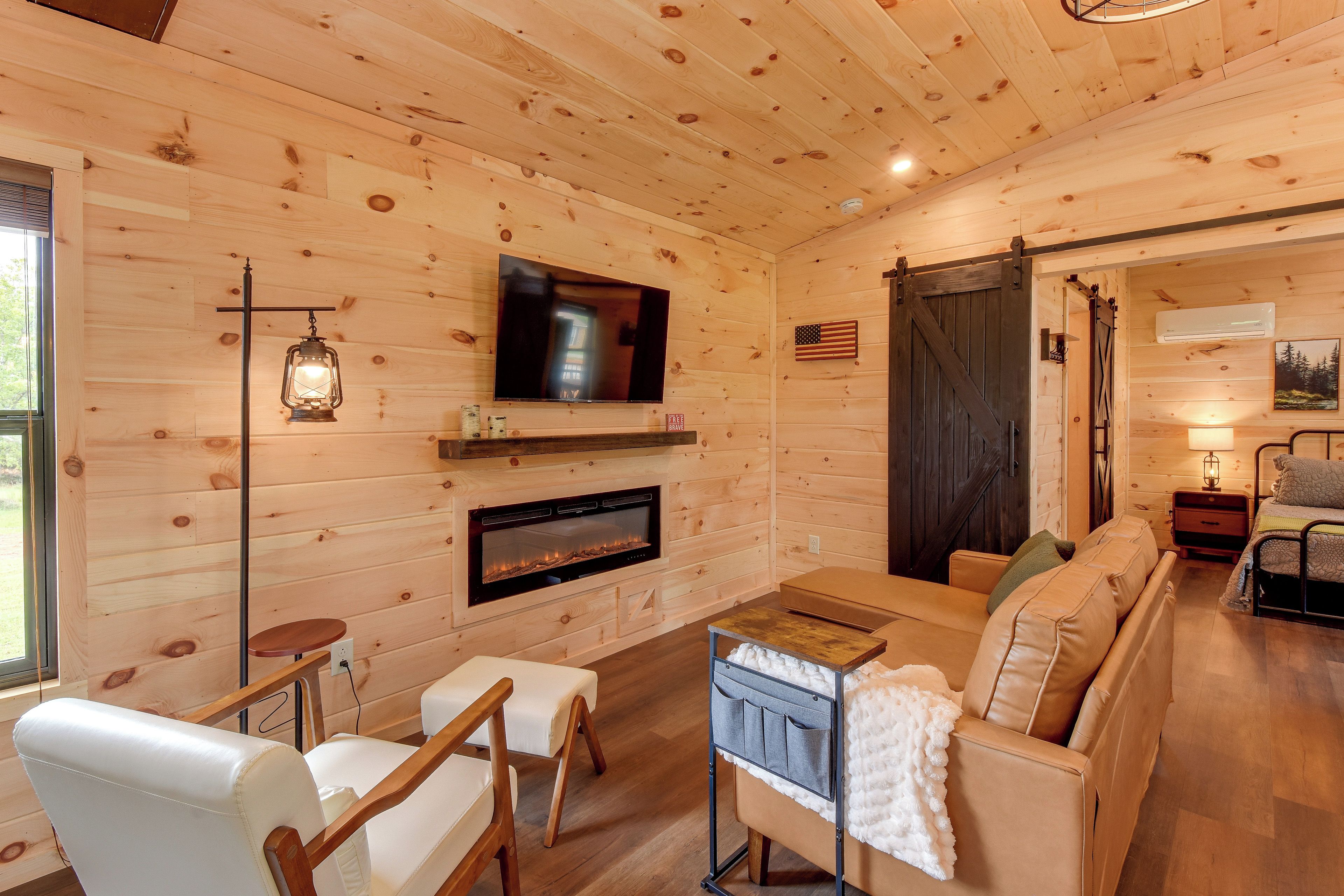 A cozy cabin interior with a fireplace, a television, and a comfortable seating area.