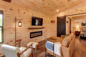 A cozy cabin interior with a fireplace, a television, and a comfortable seating area.