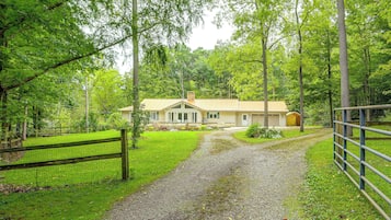 A house with a gravel driveway leading to a fenced yard.