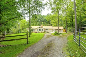 A house with a gravel driveway leading to a fenced yard. - Nature Lover's Cottage on Wooded Acreage (Nova)