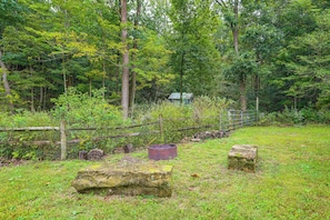 A natural setting with a wooden fence, a metal container, and a stone. - Nature Lover's Cottage on Wooded Acreage (Nova)