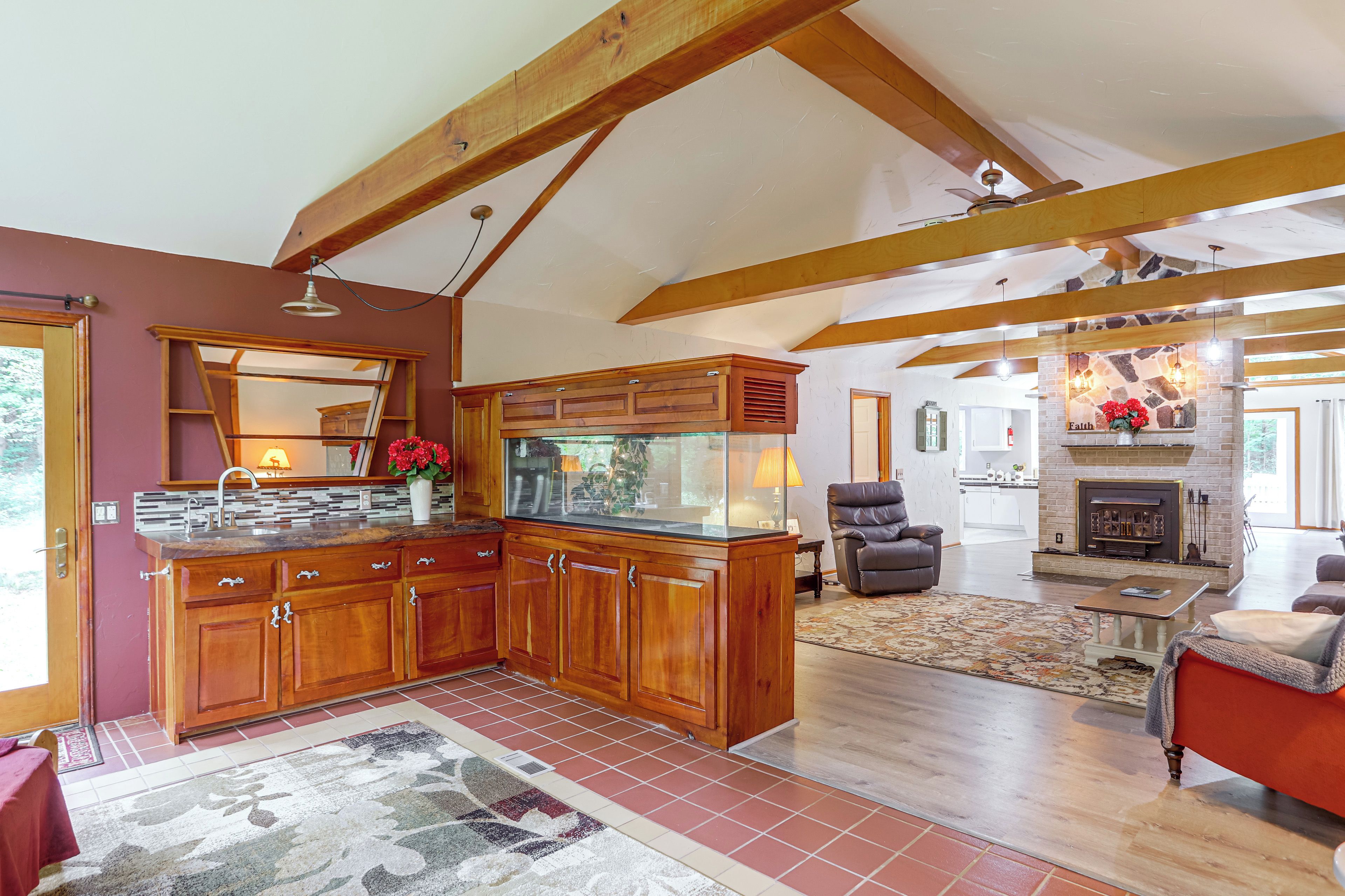 A spacious kitchen with wooden cabinets and a large island, a cozy living area with a fireplace, and a dining space with a red tablecloth.